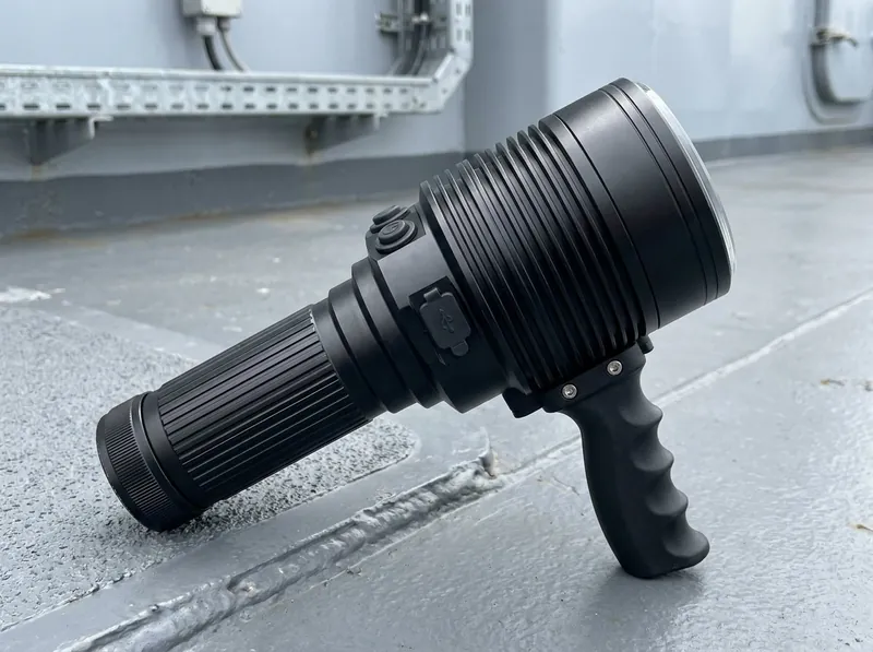 Representative render — compact damage control torch on a warship deck with deep-finned head and flat toughened lens