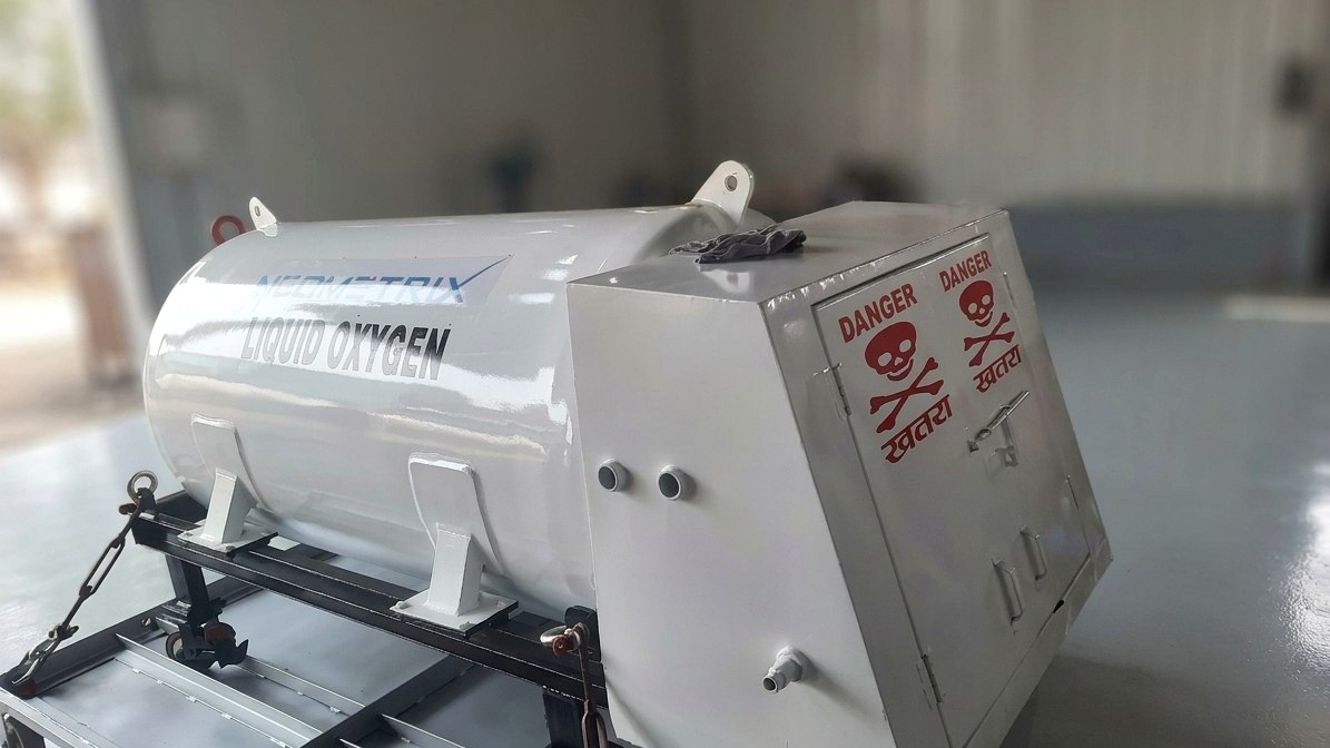 Neometrix towable liquid-oxygen dispenser unit in fabrication — white horizontal cryogenic vessel on a wheeled trolley frame with a stainless operating cabinet carrying bilingual DANGER placards
